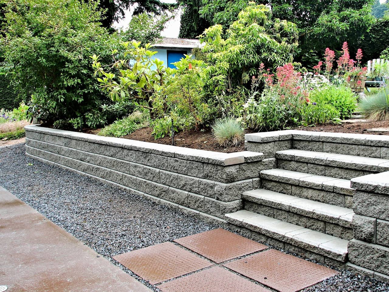 A stone wall with stairs leading up to it in a garden