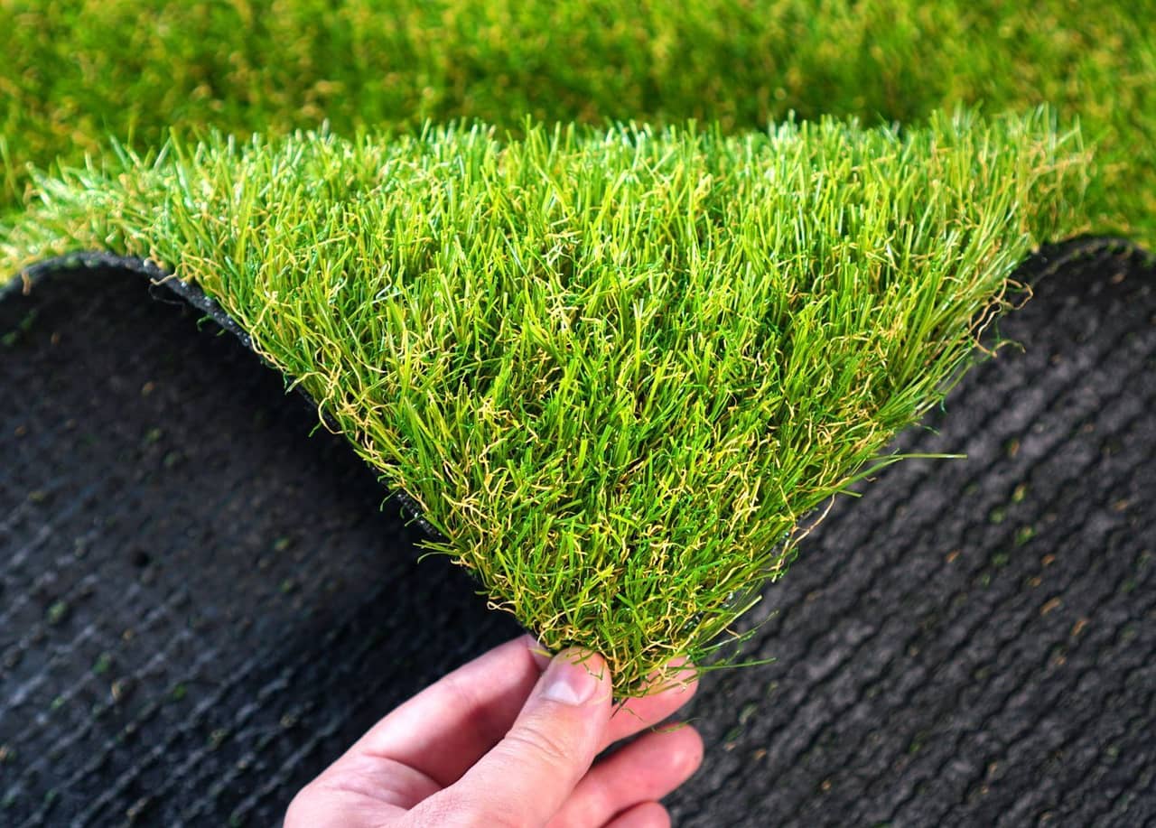 A person holding a piece of artificial grass in their hand
