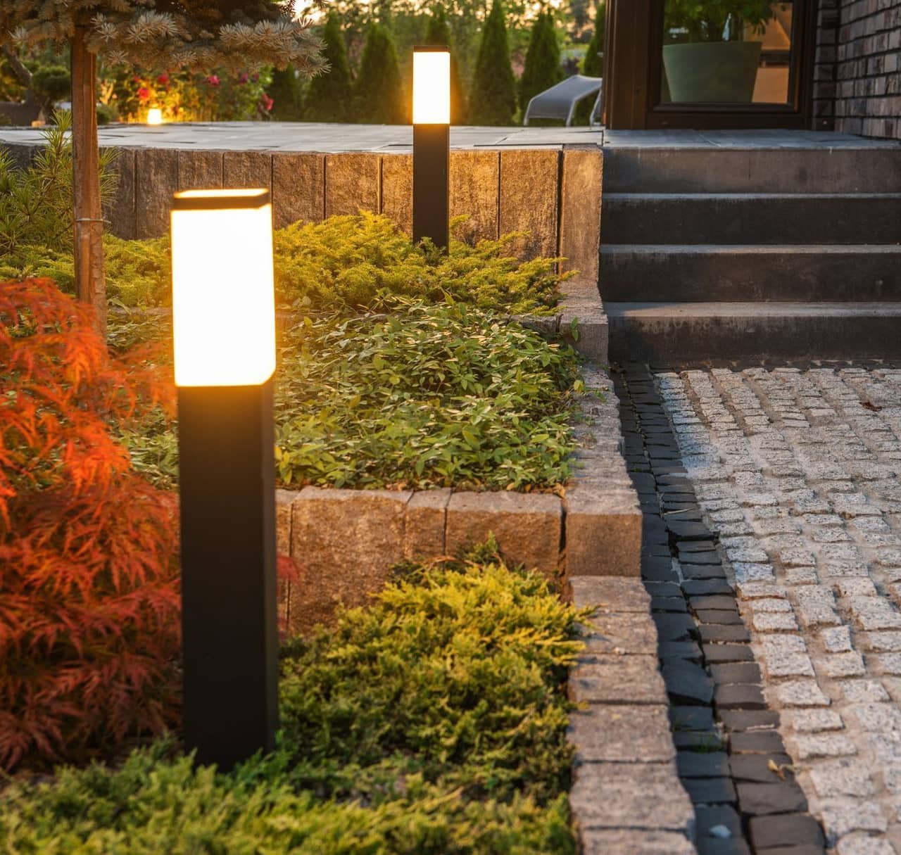 A brick walkway with a row of landscape lights illuminating the path